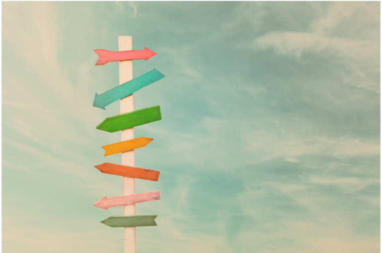 Colorful signpost with arrows pointing in different directions under a clear sky.