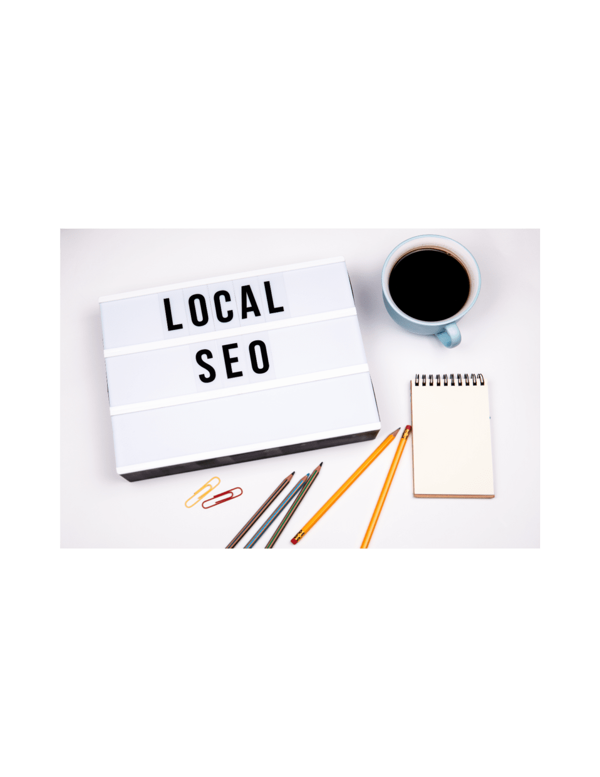 Local SEO lightbox sign on a desk with pencils, notepad, and coffee cup, representing tools for optimizing small business search rankings.