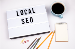 Local SEO lightbox sign on a desk with pencils, notepad, and coffee cup, representing tools for optimizing small business search rankings.