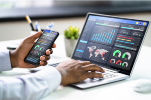 Person analyzing business performance metrics on a laptop and smartphone dashboard.